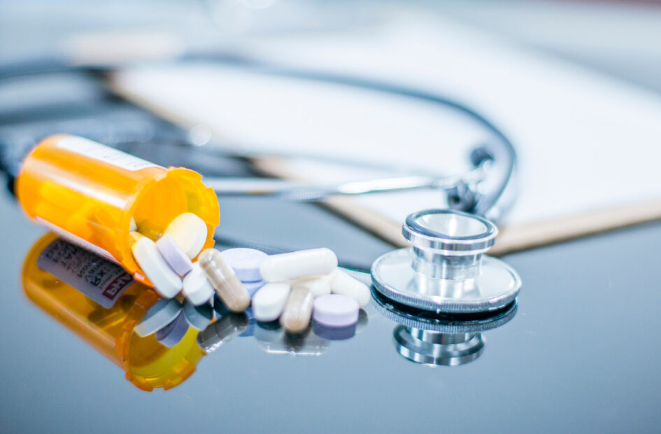 prescription bottle and stethoscope on a desk