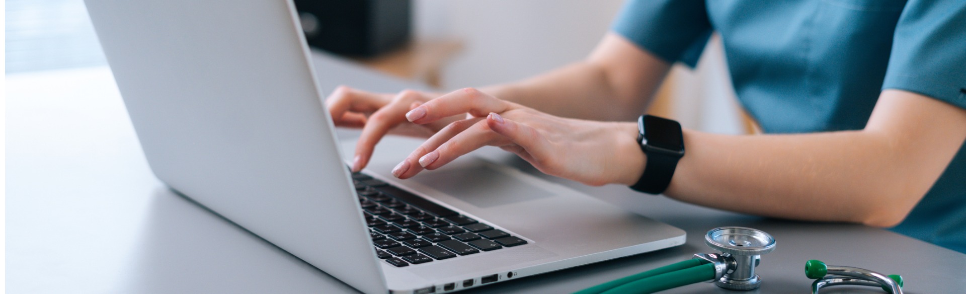 close up of female nurse hands typing on laptop