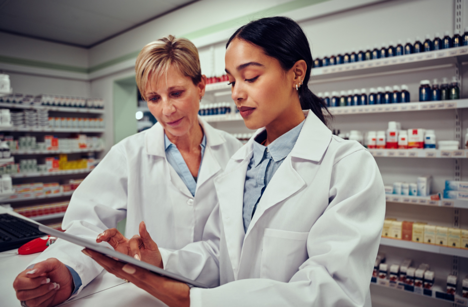 two retail pharmacists looking at a tablet device with legislative reports